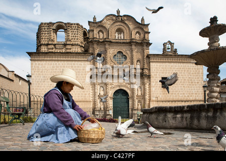 Femme indienne avec chapeau typique, vendant de la nourriture pour les pigeons en face de l'église de Belen, faits entièrement de roche volcanique Banque D'Images