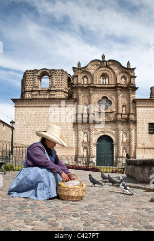 Femme indienne avec chapeau typique, vendant de la nourriture pour les pigeons en face de l'église de Belen, faits entièrement de roche volcanique Banque D'Images