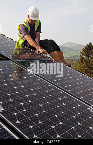 Montage des panneaux PV solaire homme à toit de maison Galles UK Banque D'Images