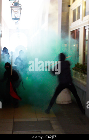 Un groupe de jeunes gens masqués habillés comme des anarchistes et vandaliser l'attaque de l'hôtel Ritz sur Piccadilly, Londres Banque D'Images