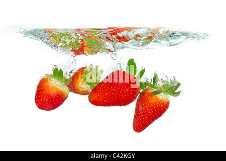 Des fraises fraîches est tombé dans l'eau avec splash sur fonds blancs Banque D'Images