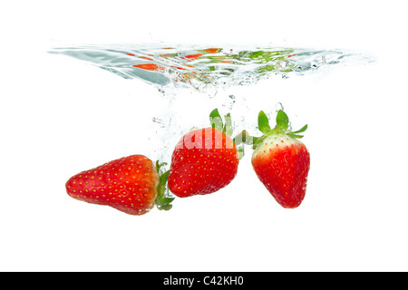 Des fraises fraîches est tombé dans l'eau avec splash sur fonds blancs Banque D'Images