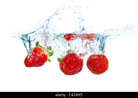 Des fraises fraîches est tombé dans l'eau avec splash sur fonds blancs Banque D'Images