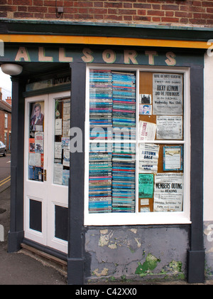 Corner shop fenêtre avec des piles de livres et affiches décolorées Banque D'Images