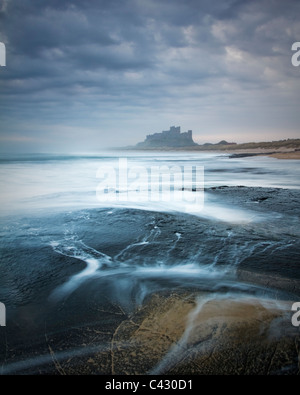 Château de Bamburgh à la première lumière à partir d'un bas plateau rock Whin nord du château, Northumberland, England Banque D'Images