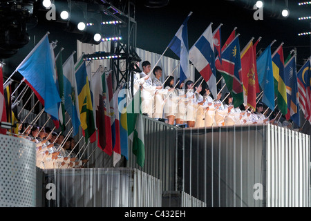 Les artistes interprètes ou exécutants en tenant le drapeau des Nations Unies alors que le drapeau olympique est soulevée au cours de la 2010 Cérémonie d'ouverture des Jeux Olympiques de la jeunesse. Banque D'Images