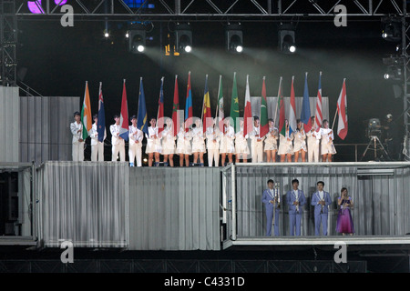 Les artistes interprètes ou exécutants en tenant le drapeau des Nations Unies alors que le drapeau olympique est soulevée au cours de la 2010 Cérémonie d'ouverture des Jeux Olympiques de la jeunesse. Banque D'Images