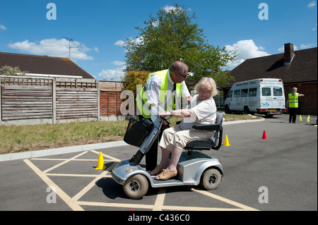 Une vieille dame (senior) apprendre à conduire un scooter de mobilité au Centre for Disability Studies à Rochford, dans l'Essex. Banque D'Images