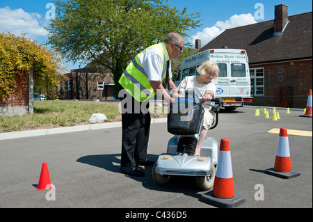 Une vieille dame (senior) apprendre à conduire un scooter de mobilité au Centre for Disability Studies à Rochford, dans l'Essex. Banque D'Images