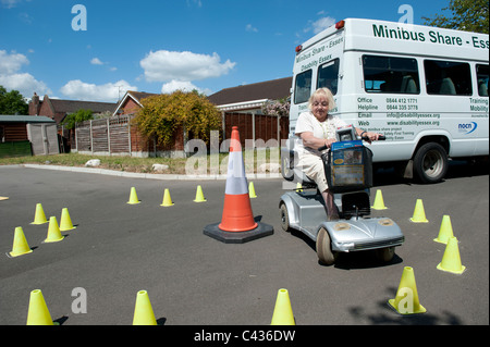 Une vieille dame (senior) apprendre à conduire un scooter de mobilité au Centre for Disability Studies à Rochford, dans l'Essex. Banque D'Images