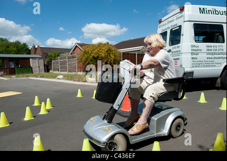 Une vieille dame (senior) apprendre à conduire un scooter de mobilité au Centre for Disability Studies à Rochford, dans l'Essex. Banque D'Images