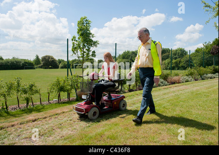 Une jeune fille handicapée subit l'enseignement dans l'utilisation sécuritaire d'un scooter de mobilité au Centre for Disability Studies au Royaume-Uni. Banque D'Images