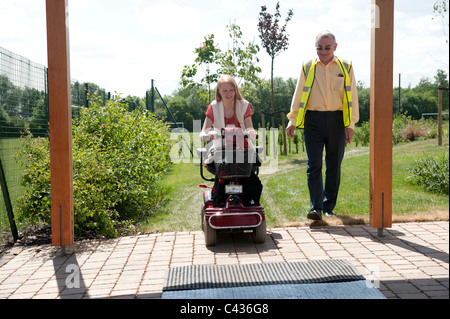 Une jeune fille handicapée subit l'enseignement dans l'utilisation sécuritaire d'un scooter de mobilité au Centre for Disability Studies au Royaume-Uni. Banque D'Images