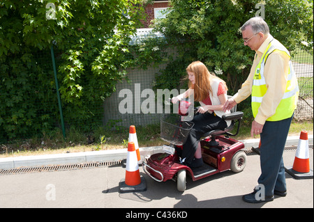 Une jeune fille handicapée subit l'enseignement dans l'utilisation sécuritaire d'un scooter de mobilité au Centre for Disability Studies au Royaume-Uni Banque D'Images