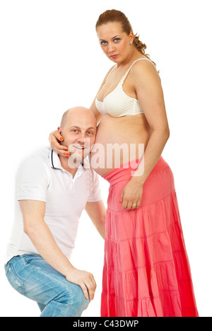 Homme heureux d'écouter son bébé à naître et mouvements holding head sur sa femme ventre isolé sur fond blanc Banque D'Images