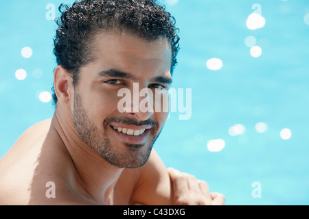 Handsome young man smiling et relaxant près de piscine de l'hôtel. De forme horizontale, la tête et épaules, copy space Banque D'Images
