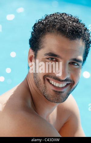 Handsome young man smiling et relaxant près de piscine de l'hôtel. La forme verticale, la tête et épaules Banque D'Images