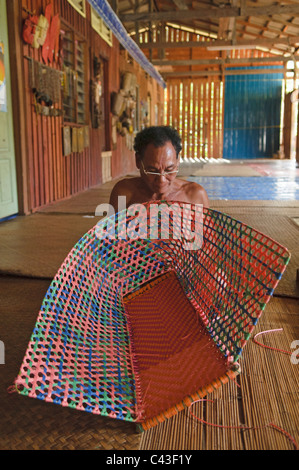 Homme Iban tisser un panier dans la Nanga Sumpa longhouse au Sarawak, Bornéo, Malaisie Banque D'Images