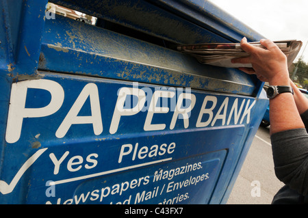 Une femme le recyclage des journaux dans une grande banque papier Banque D'Images