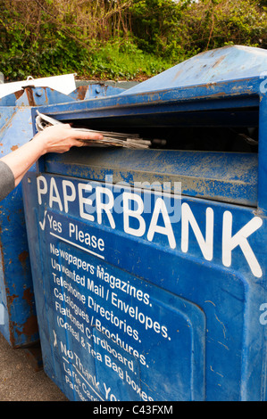 Une femme le recyclage des journaux dans une grande banque papier Banque D'Images