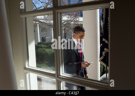 Le président Barack Obama vérifie son BlackBerry pendant qu'il marche le long de la Colonnade à l'Oval Office, 18 mars 2010. Banque D'Images