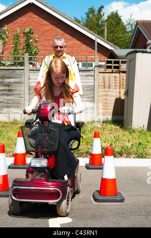 Une jeune fille handicapée subit la formation dans l'utilisation sécuritaire d'un scooter de mobilité au Centre for Disability Studies au Royaume-Uni. Banque D'Images