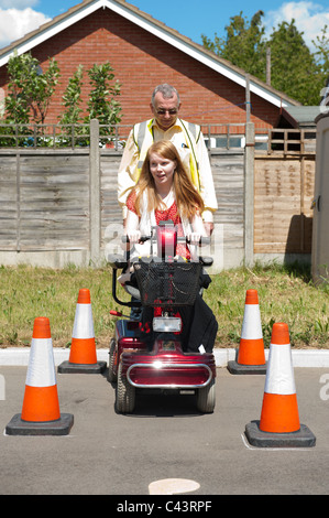 Une jeune fille handicapée subit la formation dans l'utilisation sécuritaire d'un scooter de mobilité au Centre for Disability Studies au Royaume-Uni. Banque D'Images