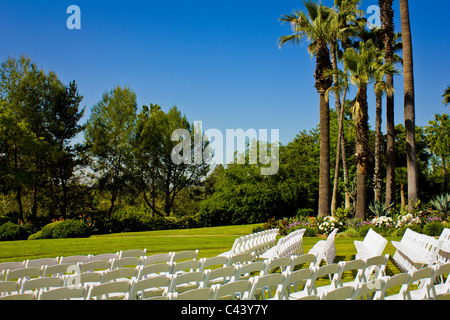 L'image d'une des rangées de chaises en mariage blanc sur un champ d'herbe. Banque D'Images