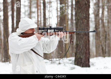 Dans Sniper camouflage blanc visant à fusil à la forêt d'hiver. Banque D'Images