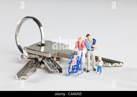 Une jeune famille de miniatures debout à côté de clés de maison sur un jeu de clés Banque D'Images