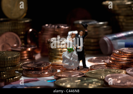 Couple de mariage miniatures figurines au milieu des piles de pièces de monnaie de l'Union européenne Banque D'Images