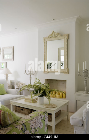 White salon avec table basse, miroir et un canapé à motifs floral. Banque D'Images