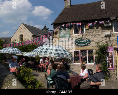 Les gens assis en terrasse de café salon avec des bâtiments ornés d'union flag bunting Bakewell Derbyshire Peak District en Angleterre Banque D'Images