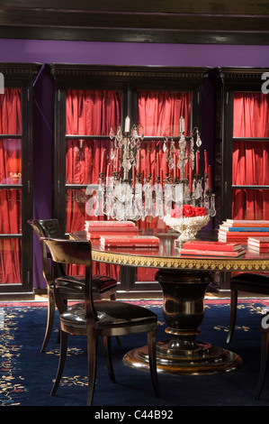 La façade de verre placards avec des rideaux en soie dans la salle à manger avec table à manger circulaire, candélabres et tapis bleu cristal Banque D'Images