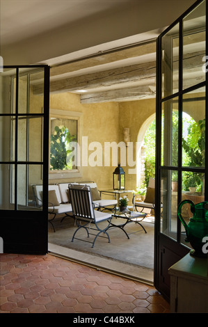 Voir à travers le verre vitrage des portes doubles donnant sur loggia avec poutres au plafond, de lanternes et de meubles de jardin Banque D'Images