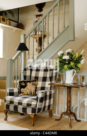 Fauteuil fauteuils rembourrés en tissu à carreaux blancs et noirs au pied d'un escalier cottage Banque D'Images