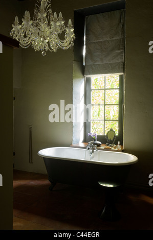 Baignoire sur pieds dans la salle de bains avec fenêtre avec store et lustre Banque D'Images