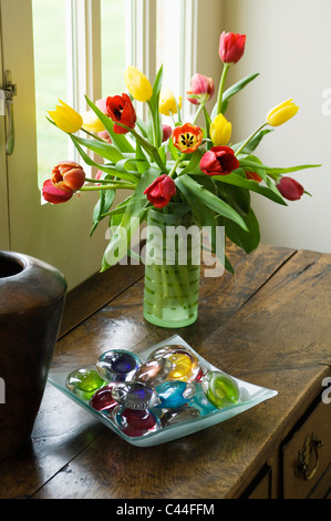 Vase de tulipes sur le vieux coffre en bois avec bol de verre colorés pebbles Banque D'Images