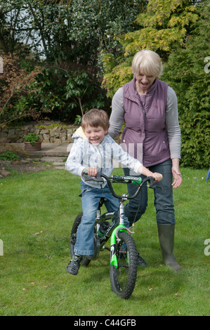 L'enseignement de la grand-mère petit-fils à faire du vélo dans un jardin arrière Banque D'Images