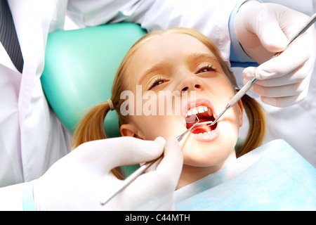 Photo de petite fille avec la bouche ouverte alors qu'il soit examiné par un dentiste Banque D'Images