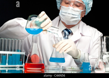 Clinicien sérieux bleu verser de liquide dans le tube de verre in laboratory Banque D'Images