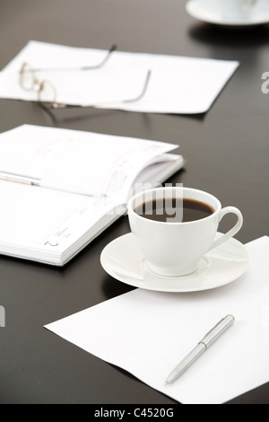 Close-up de tasse de café, papiers, portable, stylos, lunettes sur la table Banque D'Images