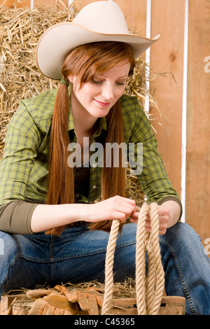 Cowgirl style jeune pays occidental assis in barn Banque D'Images