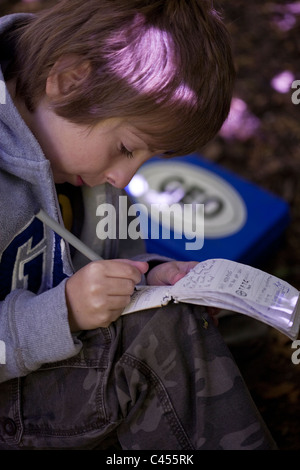 L'écriture de l'enfant dans le log book trouvé dans la zone de chasse au trésor Banque D'Images