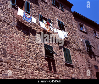 Mur de pierre d'un bâtiment à Massa Maritima avec blanchisserie accrochées sur un fil a linge pour le séchage, Toscane, Italie Banque D'Images