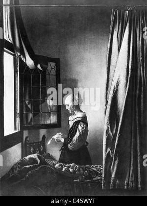 Jeune fille lisant une lettre à une fenêtre ouverte Banque D'Images