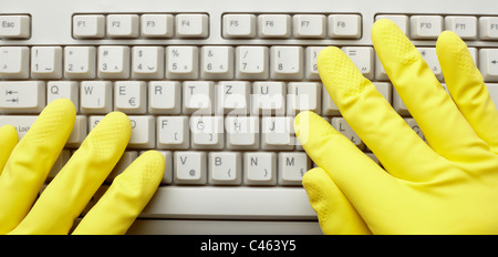 Les mains dans les gants et clavier de l'ordinateur Banque D'Images