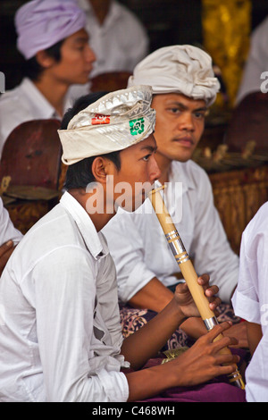 Un musicien joue BALINAIS PURA BEJI flute au temple dans le village de Mas durant la fête GALUNGAN - UBUD, BALI, INDONÉSIE Banque D'Images