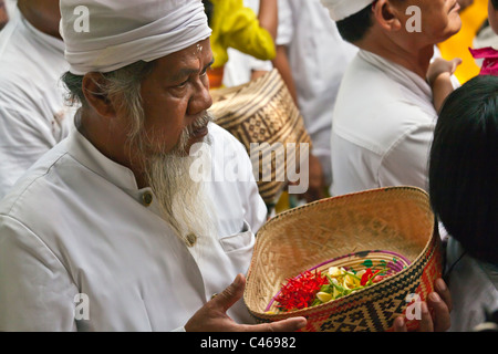 Un homme apporte des offrandes à BALINAIS PURA BEJI dans le village de Mas durant la fête GALUNGAN - UBUD, BALI, INDONÉSIE Banque D'Images