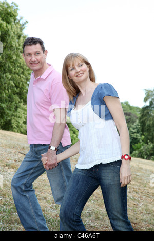 Couple en train de marcher dans la campagne, en souriant. Banque D'Images